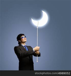 Concept of dream. Image of young businessman in goggles looking at moon