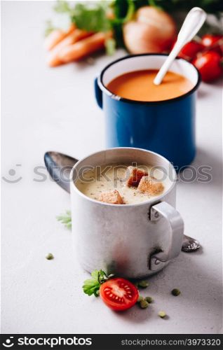 Concept of healthy vegetable and legume soups. Pea and tomato soups and ingredients. Pea and tomato soups and ingredients on concrete background