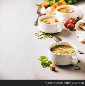 Concept of healthy vegetable and legume soups. Pea, tomato, vegetable soups and ingredients. Pea, tomato, vegetable soups and ingredients on concrete background