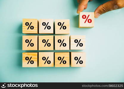 Concept of interest rate and financial ranking. Businessman’s hand placing a wooden cube block with a percentage symbol icon, highlighting the importance of monitoring rates.