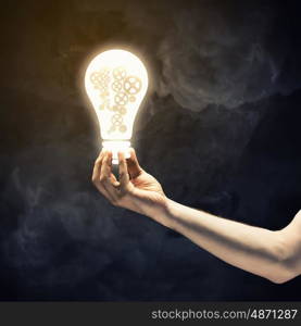 Concept of mechanism light bulb with gears inside in human hand. Light bulb with cogwheels