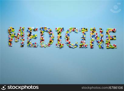 Concept of medicine and healthcare. Word medicine spelled with capsules and pills on blue background. 3d render