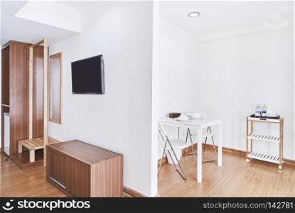Concept of modern living apartment room decoration with built-in furniture, TV and table set with chairs mock up in the white room