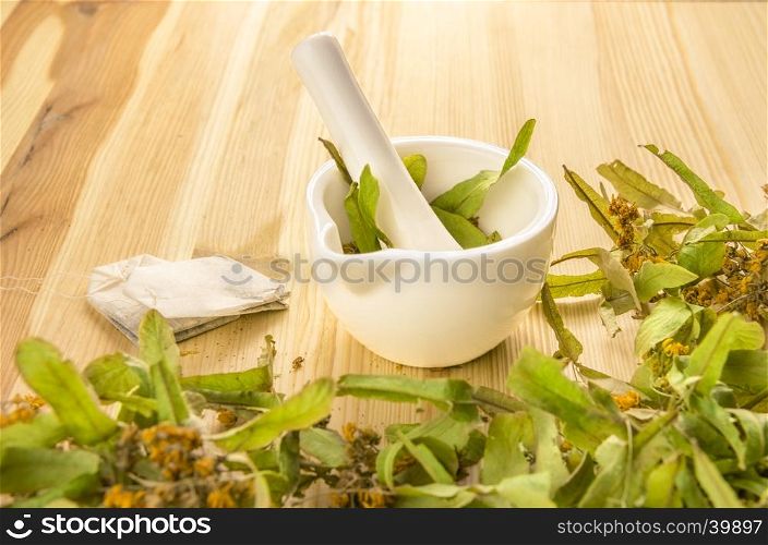 Concept of natural and organic tea products. A couple of tea bags obtained from grinding linden flowers in a mortar, on a wooden table.