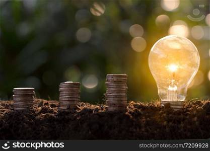 concept of new ideas and innovations with the growth of coins and light bulbs.Stacked of coins and light bulbs on the soil ,ground.Light bulb with heap of coins stairs for financial plan or business .