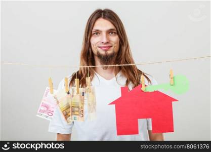 Concept of real estate and deal. Seller man with house model and banknotes. Selling and buying proposition.. Man seller with money and house