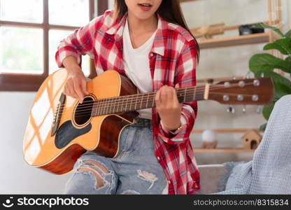 Concept of relaxation with music, Young asian woman practice playing chords with acoustic guitar.