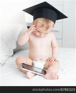 Concept of talented children. Smart baby boy in graduation cap using digital tablet