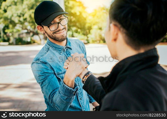 Concept of two friends greeting each other and shaking hands on the street. Two teenage friends shaking hands at each other outdoors. Two people shaking hands on the street