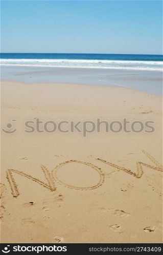 concept of vacations, background saying now on a sandy beach