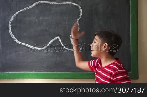 Concept on blackboard at school. Young people, student and pupil in classroom. Hispanic boy yelling, screaming, shouting in class. Portrait of frustrated male child during verbal fight and argument