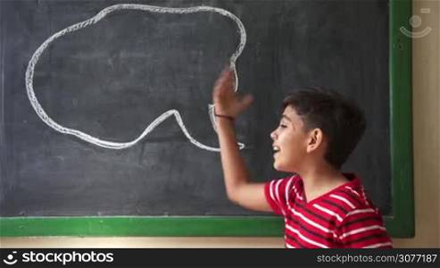 Concept on blackboard at school. Young people, student and pupil in classroom. Hispanic boy yelling, screaming, shouting in class. Portrait of frustrated male child during verbal fight and argument