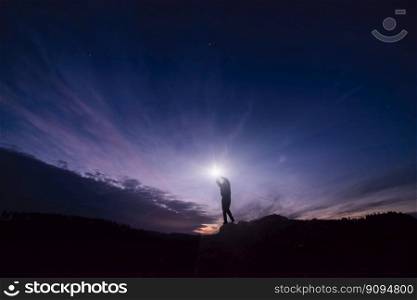 Concept Reaching for the Stars. Silhouette of a male figure reaching out to a star in a beautiful night landscape. Man on top of mountain reaching for star. 