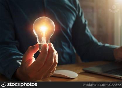 concept saving energy with innovation and inspiration. businessman holding lightbulb in office