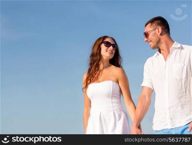 concept - smiling couple wearing sunglasses walking outdoors