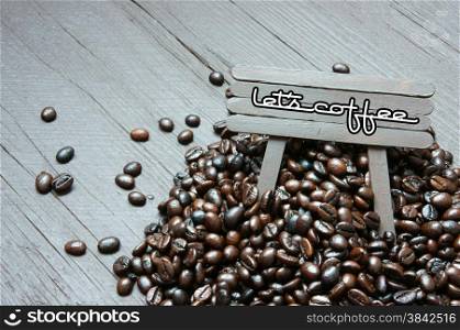 Concept with coffee bean on wooden background, idea with logo let&rsquo;s coffee on wood pano, brown bean, cafe is beverage popular with caffeine, can make mind awake