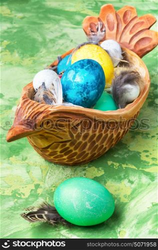 Concept with Easter eggs. Easter colored egg in a wooden symbolic chicken
