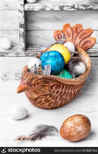 Concept with Easter eggs. Easter colored egg in a wooden symbolic chicken.Happy Easter
