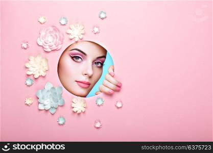 Conceptual Beauty Portrait of Beautiful Young Woman. Face of Girl with Spring Pink Make-up. Beauty Fashion Model Woman Face perfect Skin. Paper Flowers on Pink Background