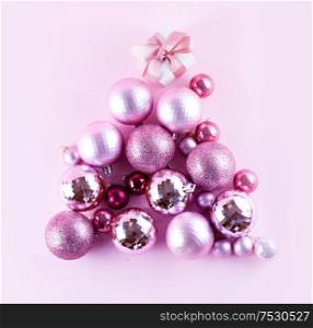 Conceptual Christmas tree of decarative balls on plain pink background. Conceptual Christmas tree