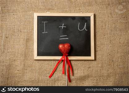 Conceptual equation of love written on blackboard with red heart
