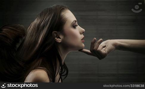 Conceptual image of a hand holding a woman&acute;s head