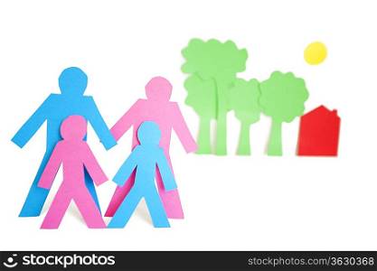 Conceptual image of paper cut out shapes representing a family with trees and house over white background