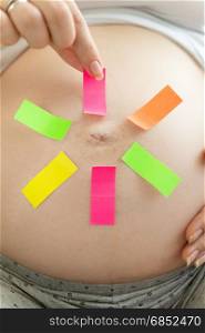 Conceptual image of pregnant woman making choice on colorful memo stickers