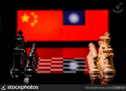 Conceptual image of war between China and Taiwan using chess pieces and national flags on a reflective background