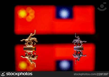 Conceptual image of war between China and Taiwan using toy soldiers and national flags on a reflective background