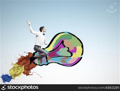 Conceptual image of young businessman riding light bulb. Master of creativity