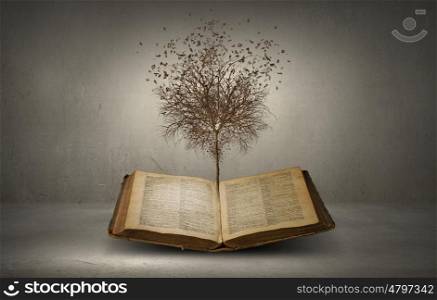 Conceptual image with dry tree growing from book. Reading and self education
