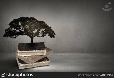 Conceptual image with green tree growing from book. Reading and self education