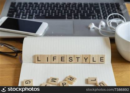 Conceptual keyword lifestyle in wooden tile letters  in personal home desk setting with laptop, notebook and accessories