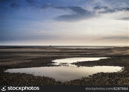 Conceptual landscape image of two people on remote beach