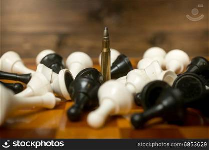Conceptual photo of bullet among lying down chess pieces