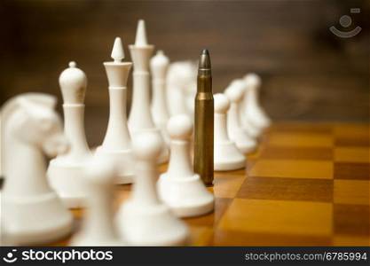 Conceptual photo of bullet in row of white pawns. Concept of military conflict