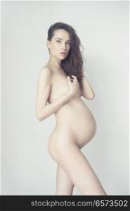 Conceptual photo of elegant naked pregnant woman. Beautiful pregnancy. Love and care