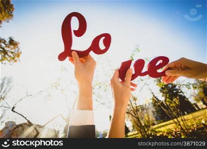 "Conceptual photo of man and woman holding two halves of "Love" sign"