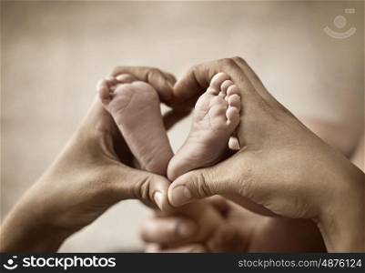 Conceptual photo of parent's hands holding little feet
