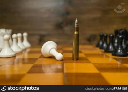 Conceptual photo of riffle bullet on chessboard. Concept of power of guns