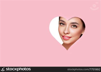 Conceptual photo of Valentine’s day. Face of Girl with Festive Pink Makeup. Paper hearts on a pink background. Love symbols Valentines day