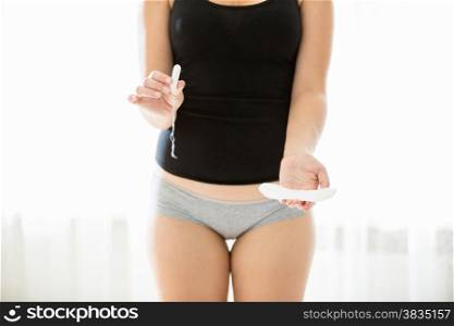 Conceptual photo of woman choosing between tampon and pad