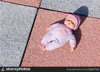 conceptual picture of an old and abandoned doll on a children playground regarding childhood, violence and abuse