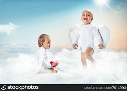 Conceptual portrait of a two cheerful cupids on the cloud