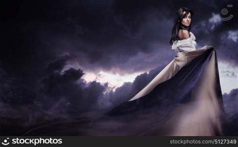 Conceptual portrait of a young lady posing over the dark sky