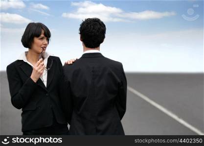 Conceptual shot of a business couple standing facing different directions on a highway