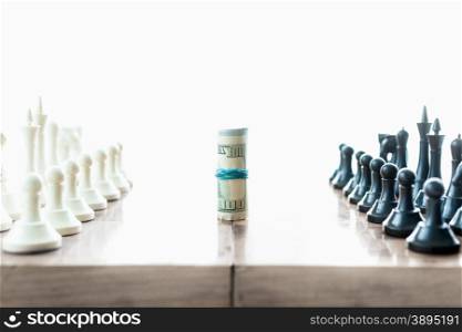 Conceptual shot of chess pieces fighting for twisted dollar bills