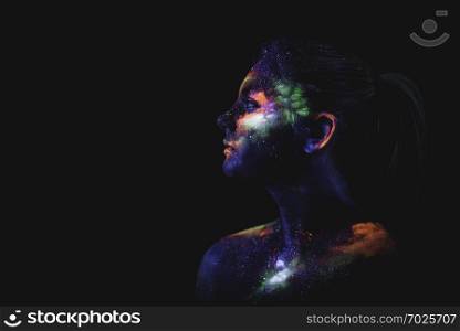 Conceptual shot of light and shine fluorescent colors young girl&rsquo;s face. Portrait of a girl painted in fluorescent UV colors.