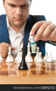 Conceptual shot of money power. Man making chess move with dollar banknotes